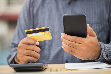 关闭商人手拿着信用卡和使用智能手机到财务管理网上购物图片