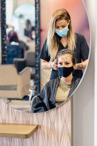 女理发师在美容中心用吹风机吹干客户的头发图片