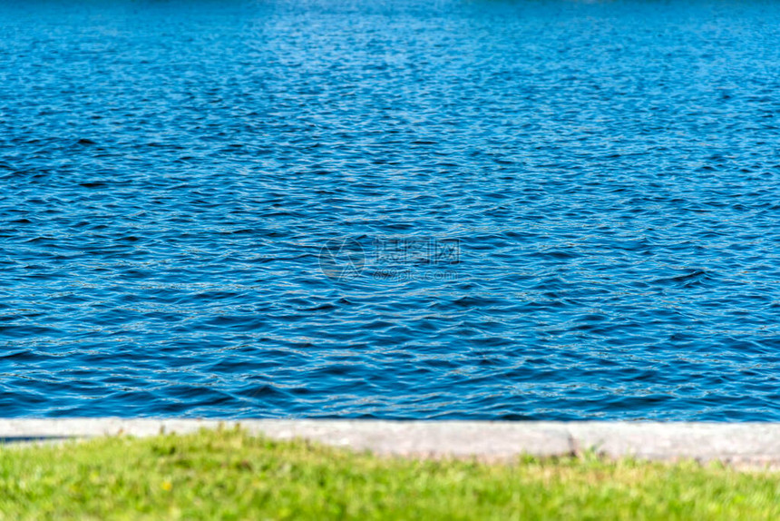 绿草与湖水分开的草坪是一个小石滩图片