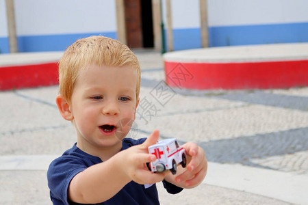 一个迷人的金发男孩的画像一个三岁的男孩正在玩具车图片