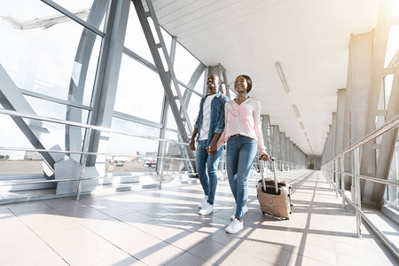 浪漫的非洲夫妇带着手提箱走到机场登机口图片