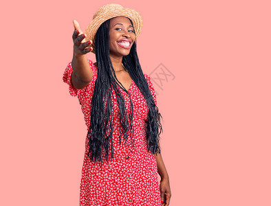 穿着暑期帽的年轻非洲女微笑着友好地握手图片