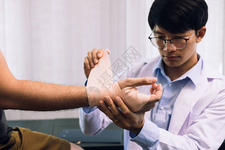 整蛊男孩亚洲物理治疗师正在检查患者手背景