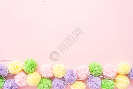 粉红色背景上的柔和彩色绒球背景图片