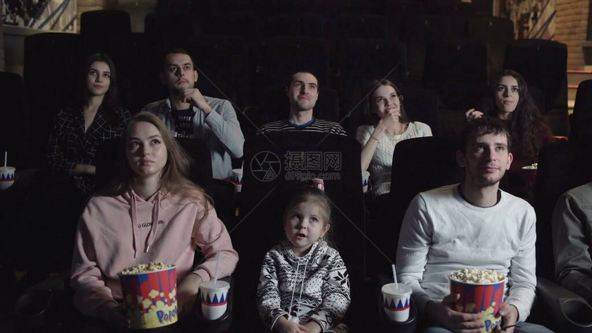 年轻人坐在电影院看电影吃爆米花友谊和图片