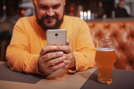 在啤酒吧使用智能手机拍摄一个快乐的图片