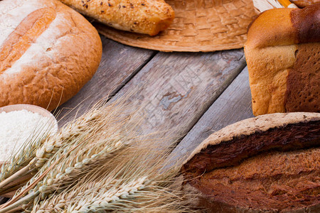 什锦新鲜面包和麦穗自制面包分类和质朴的木桌上的小麦穗图片