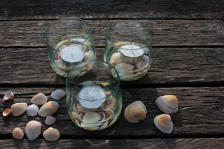 在海滩木制码头上戴眼镜和贝壳的茶烛图片