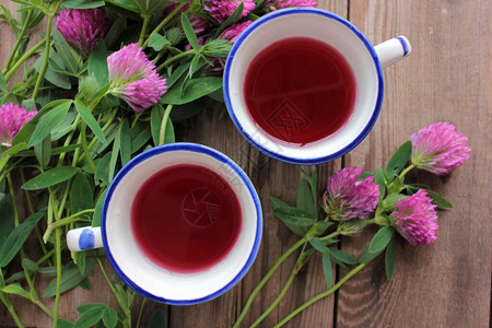 两杯愈合草药茶或灌入红花朵木制桌上的紫花天然花卉背图片