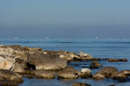 石海岸和渔民在地平线上的小船典型的海滨小镇景观在岸边钓鱼海和大石图片
