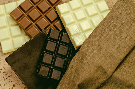 不同的牛奶和黑巧克力木制背景上的巧克力片粗麻布巴的黑巧克力牛奶巧克力图片