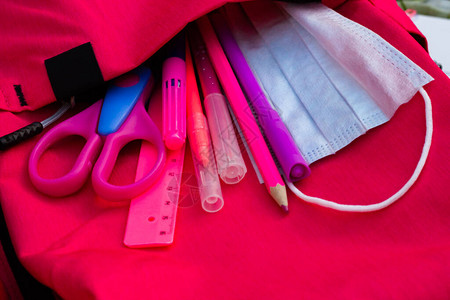 粉红学校用品和装在粉红色背包中的医疗面具图片