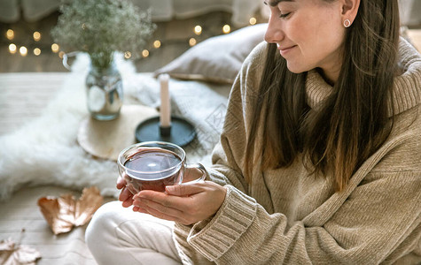 温馨的秋天家庭气氛一个手拿着一杯茶的女人休息和舒适的概念图片