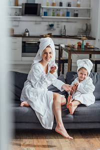 在沙发上与女儿坐在浴袍和头顶毛巾上时图片