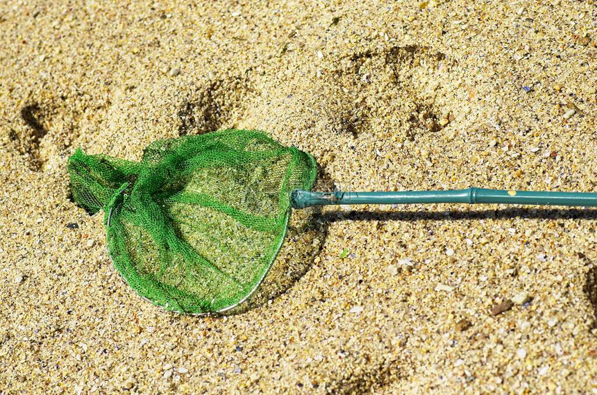 沙滩上的绿色渔网钓鱼工具图片