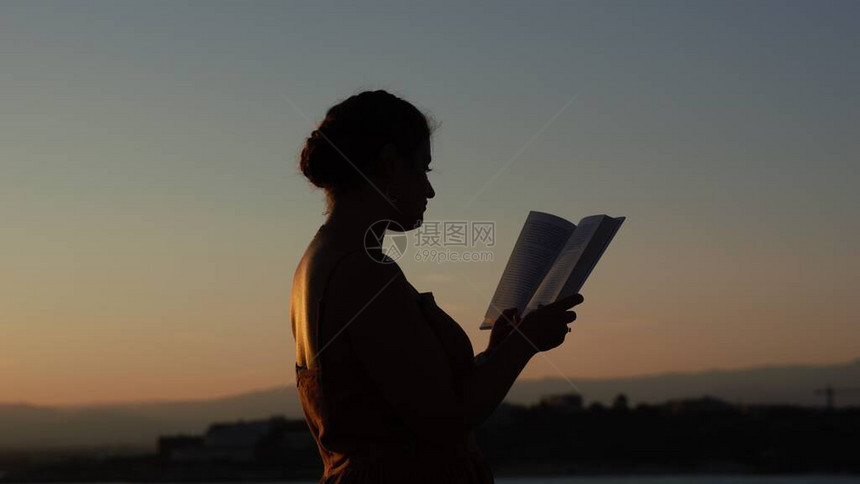 湖边读诗的年轻女子剪影图片