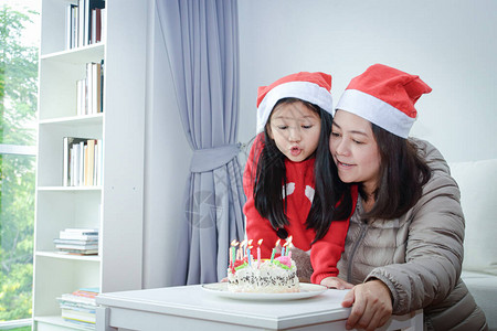 母亲和女儿在圣诞节上吹生日蛋糕图片