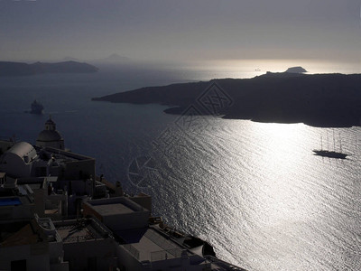 一艘豪华游轮的剪影在费拉附近的一个海湾日落时欣赏地中海岛屿和图片