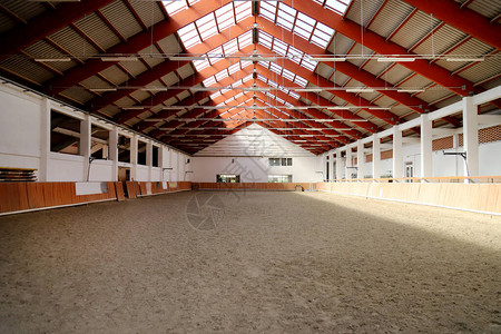 在空旷的室内骑马中心观看马匹和骑手骑术学校图片