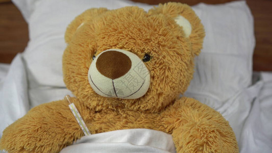 泰迪熊用汞温度计测量温度熊躺在床图片