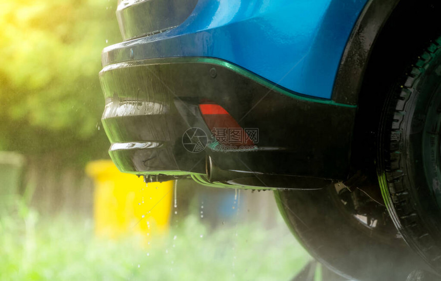 蓝色的汽车正在用水清洗汽车保养业务用高压喷水清洗后有水滴的汽车在室外的汽车清洁服务使用防腐剂的图片