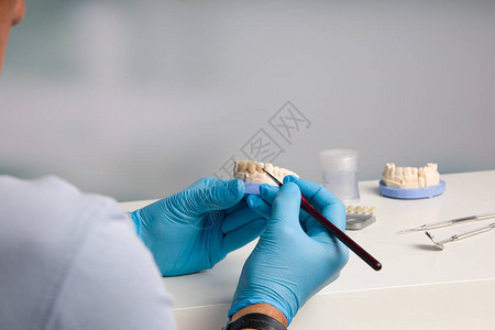 在牙科化验室做牙冠上画作的牙科技术员近距离图片