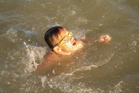 一个10岁的英俊男孩以不同的方式在海中游泳在背图片