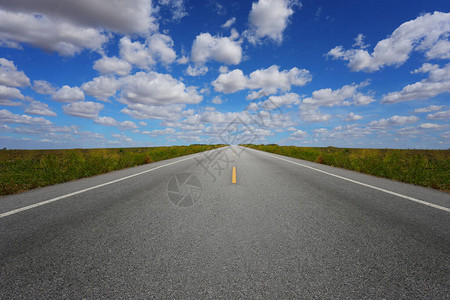 Meadow两边的农村公路白天在蓝天空中与Mead图片