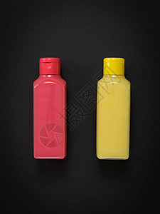 黑色背景的粉色和黄色塑料瓶子用于储存液图片