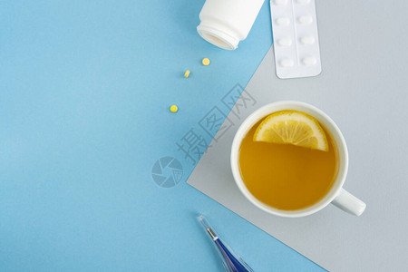 热茶和柠檬杯温度计浅蓝色背景的药片的治疗和预防复制空间图片