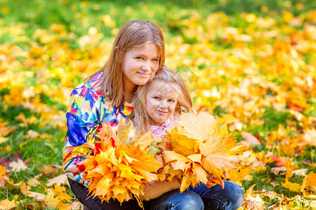 秋天的小女孩姐妹在森林中玩耍落叶子图片