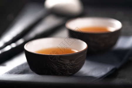 亚洲茶叶仪式瓷器茶杯和深黑石本底的图片