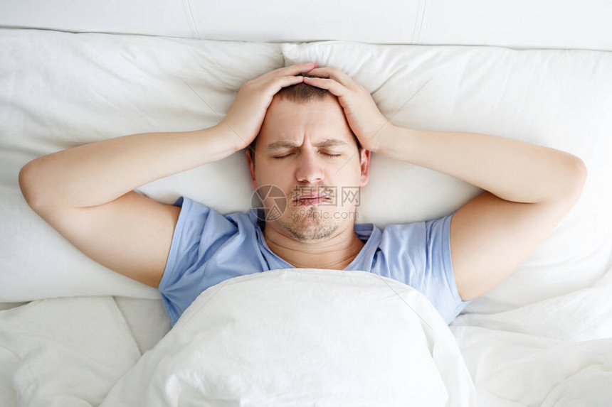 失眠抑郁或头痛概念躺在床上的有压力的青年男图片