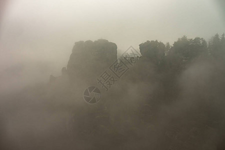 陡峭的山崖消失在低云中岩石块状的轮廓图片