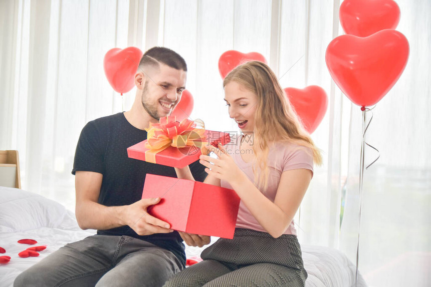 在爱情人节的概念中情侣在卧室里赠送礼物盒图片