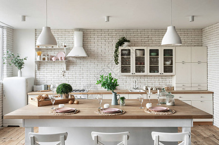 家里的现代厨房配有白色内饰冰箱餐桌上的餐具架子上的厨具用品和橱柜家具图片