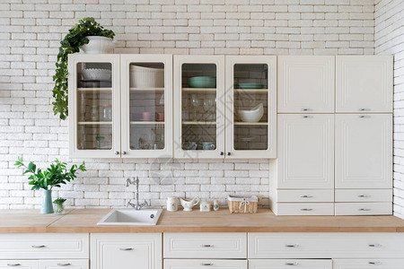 水槽水龙头台面上的厨具用品和橱柜家具上的绿色植物现代住宅的新厨柜图片