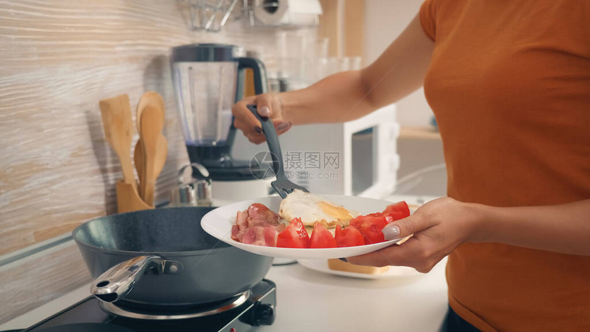 家庭主妇在厨房里煮鸡蛋作为早餐图片