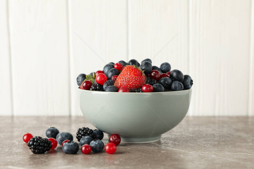 灰色桌上有新鲜浆果的碗图片