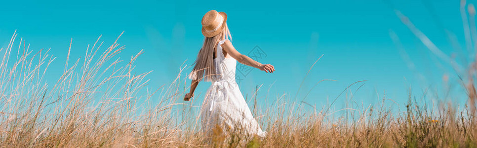 身着白裙子和草帽的女子在网站头顶上站立图片