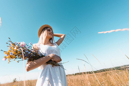高角度观察年轻女子的青春花朵与草帽相触图片
