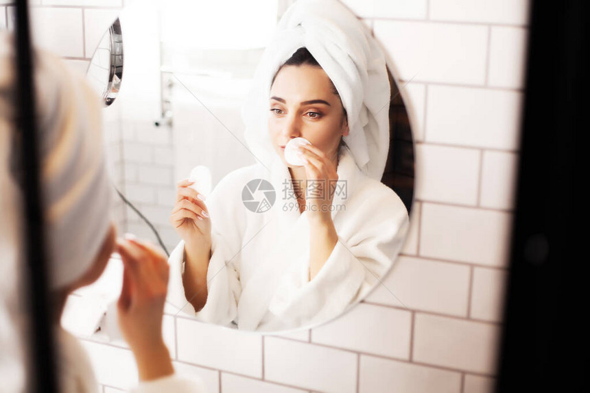 微笑的年轻女子洗脸在浴室用面部图片