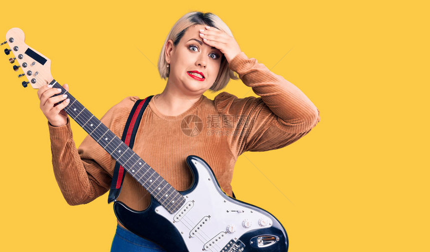 弹电吉他的金发碧眼身材魁梧的年轻女手放在头上图片