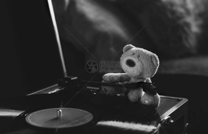 晨光的静物照穿过孤独的泰迪熊坐在旋转的黑胶唱片播放器上图片