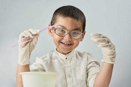 带着眼镜的有趣的书呆子小孩在讲习班上做实验探索化学世界图片