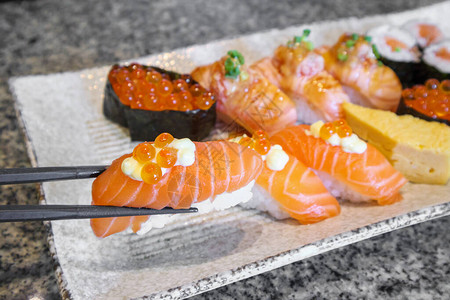 三文鱼生片寿司卷用筷子放在盘子日本料理上图片