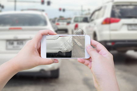 手用移动智能电话拍摄车祸事故损坏的照片图片