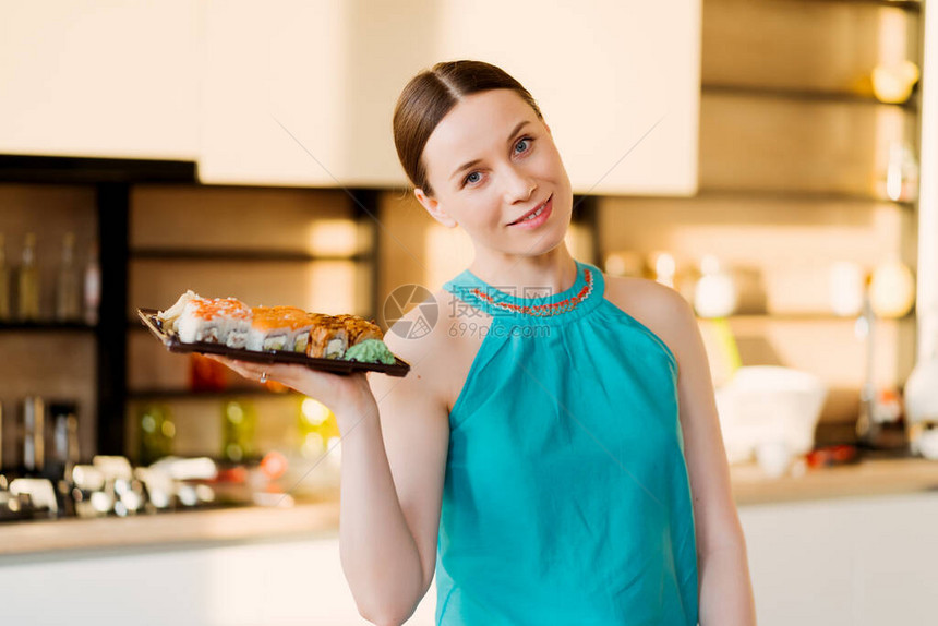 肖像有色魅力的女士将一个带有寿司卷的盘子展示在她的手中图片