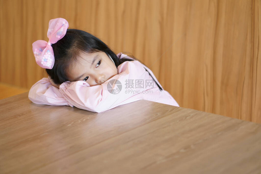 亚洲儿童可爱或小女孩睡不着觉或心不在焉地在幼儿园教室的桌子上放松图片