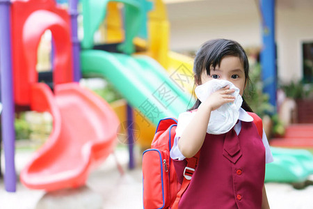 沙尘天气逆风亚洲儿童学生或小女孩因流感和沙尘天气中的弱或和细菌而在幼儿园学龄前因鼻子打喷嚏和手帕面罩上感背景